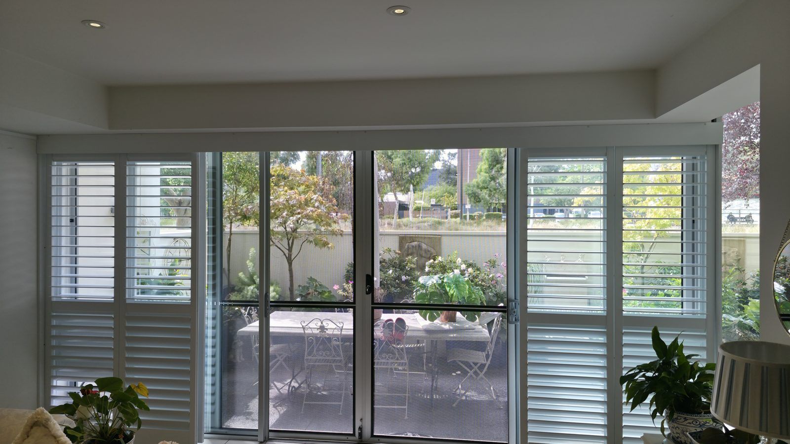 Sliding door plantation shutters opening onto a garden courtyard