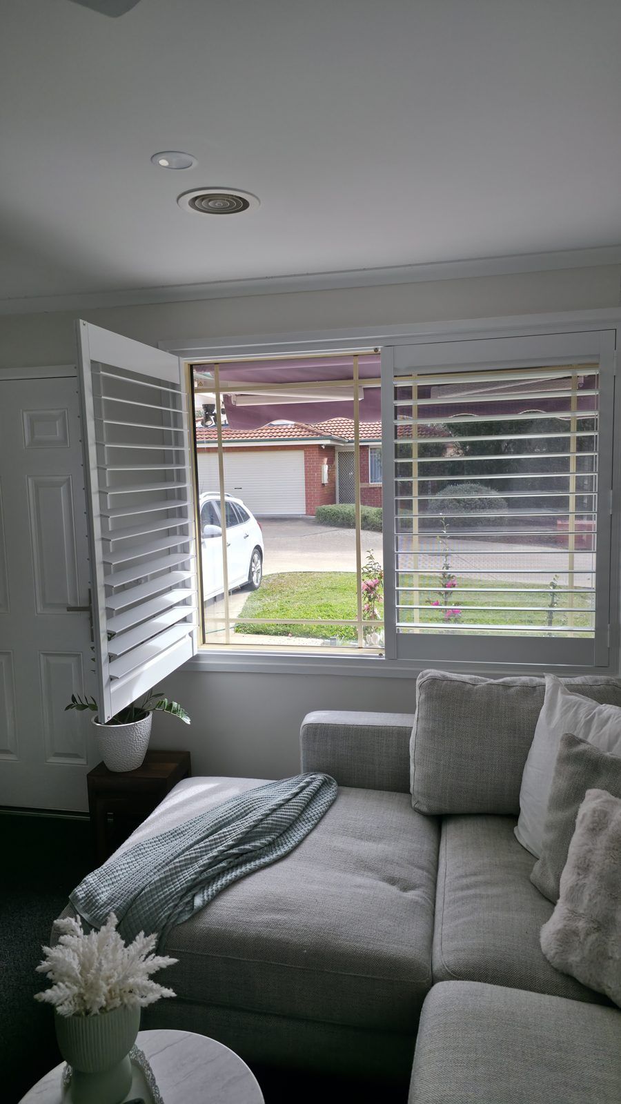 Entry-side lounge window with plantation shutters and sheer light