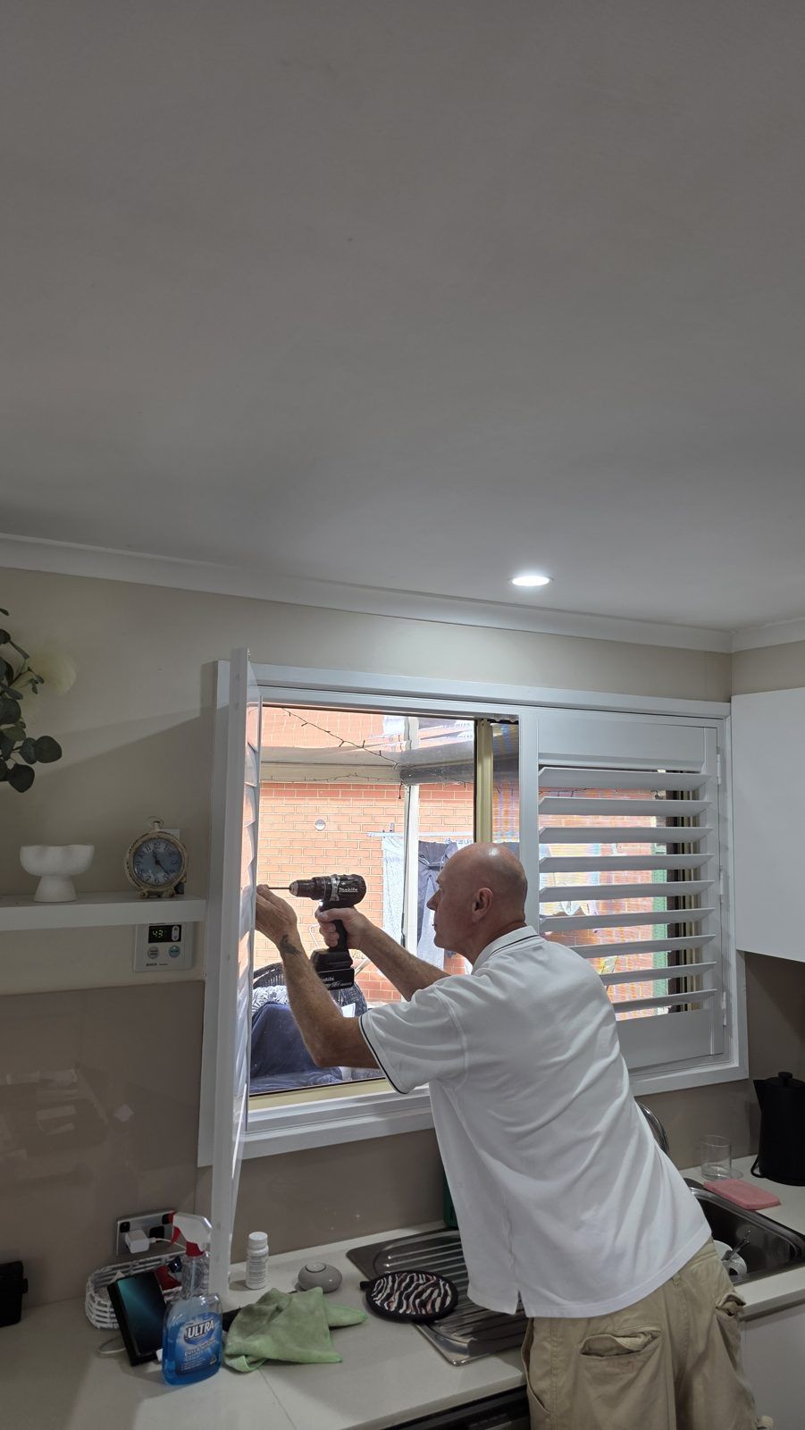 Stefan fitting plantation shutters to a kitchen window