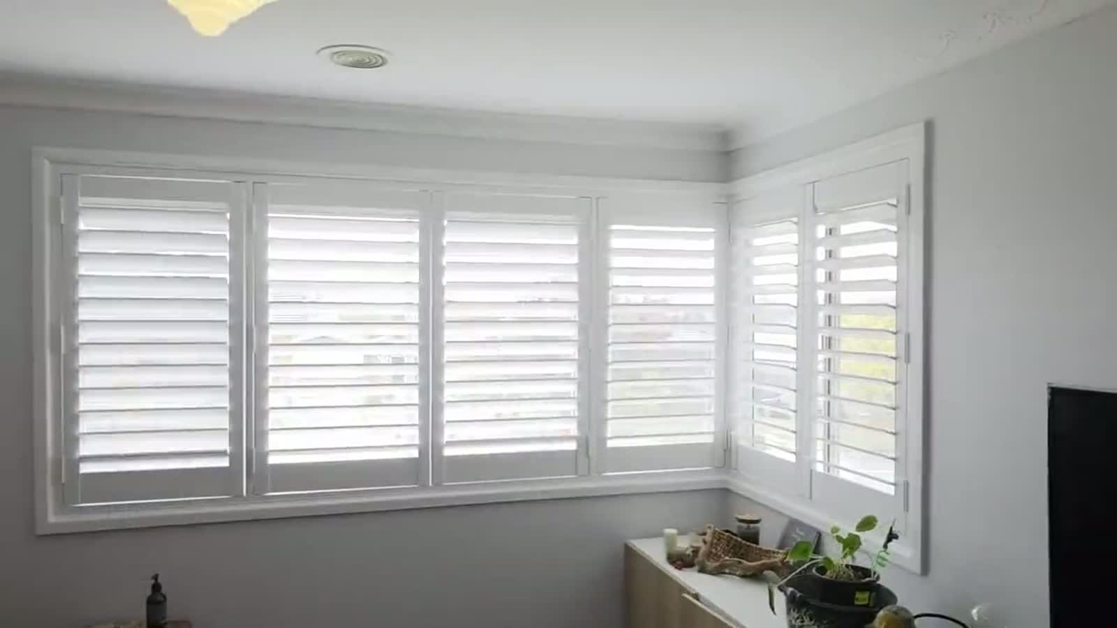 Plantation shutters fitted across a wide bay window in a Canberra home